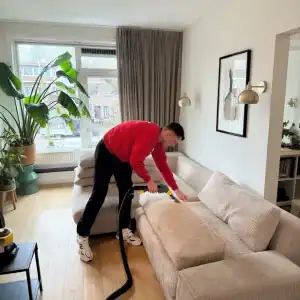 Schone woonkamer met professionele stofzuiger en schoonmaakactie.