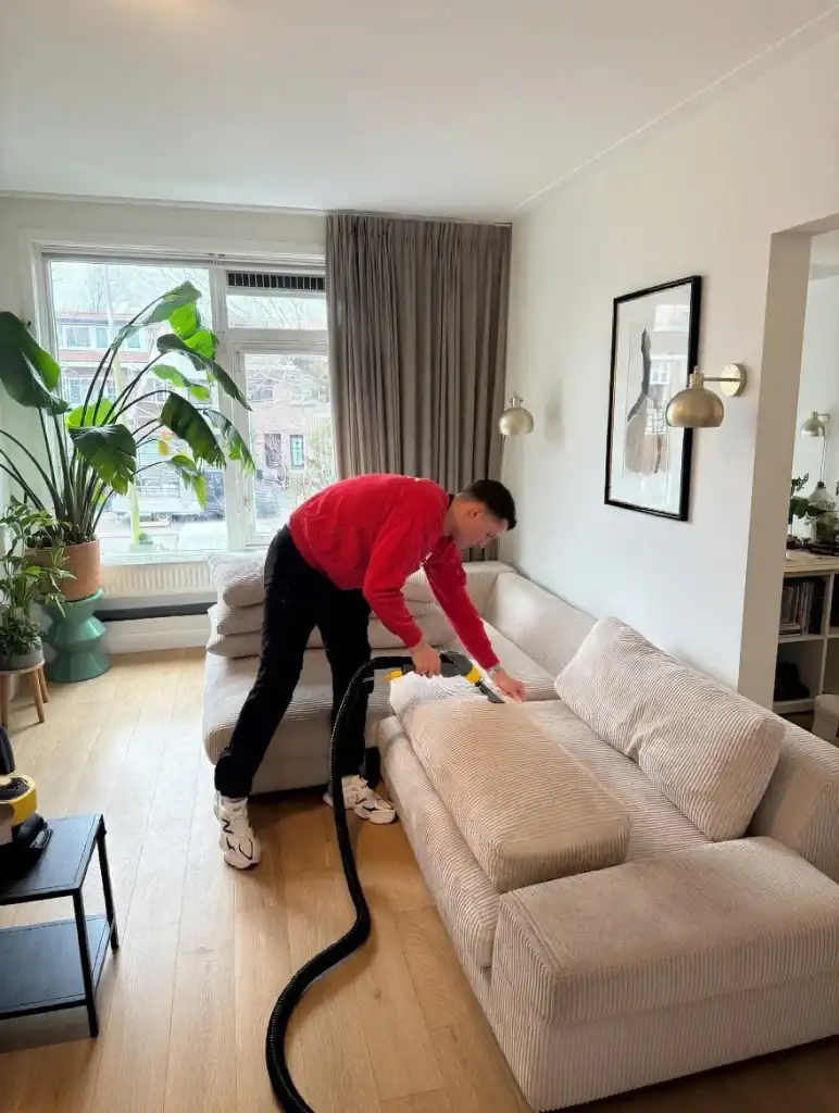 Man die bank in woonkamer stofzuigt met krachtige stofzuiger.